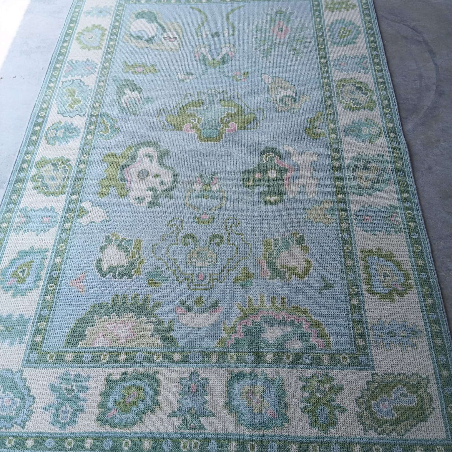Handwoven sky blue and sage green Oushak wool rug with traditional Turkish floral border design