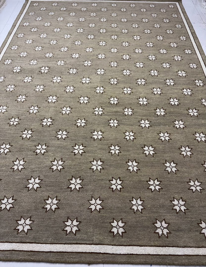 : Full pattern of a taupe geometric rug with evenly repeated ivory star-shaped motifs.