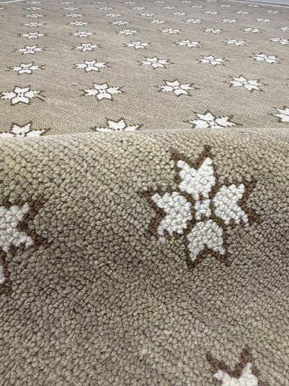 Close-up of taupe rug texture with an ivory star motif outlined in dark brown.