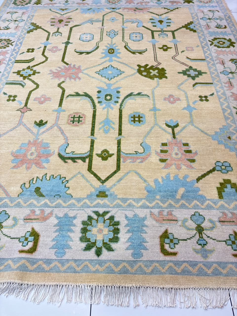 Traditional center medallion and floral motifs on handmade ivory Oushak rug.