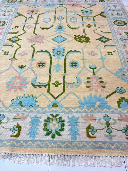Traditional center medallion and floral motifs on handmade ivory Oushak rug.