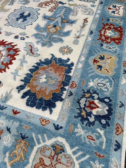 Corner detail of handmade Oushak rug with decorative floral border and ivory field