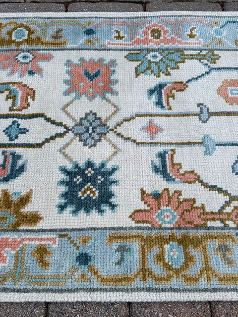 Detailed floral border of a handmade ivory and sky blue vintage runner rug.