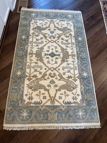 Handmade Tribal Oushak Rug in blue and ivory with animal motifs and decorative border