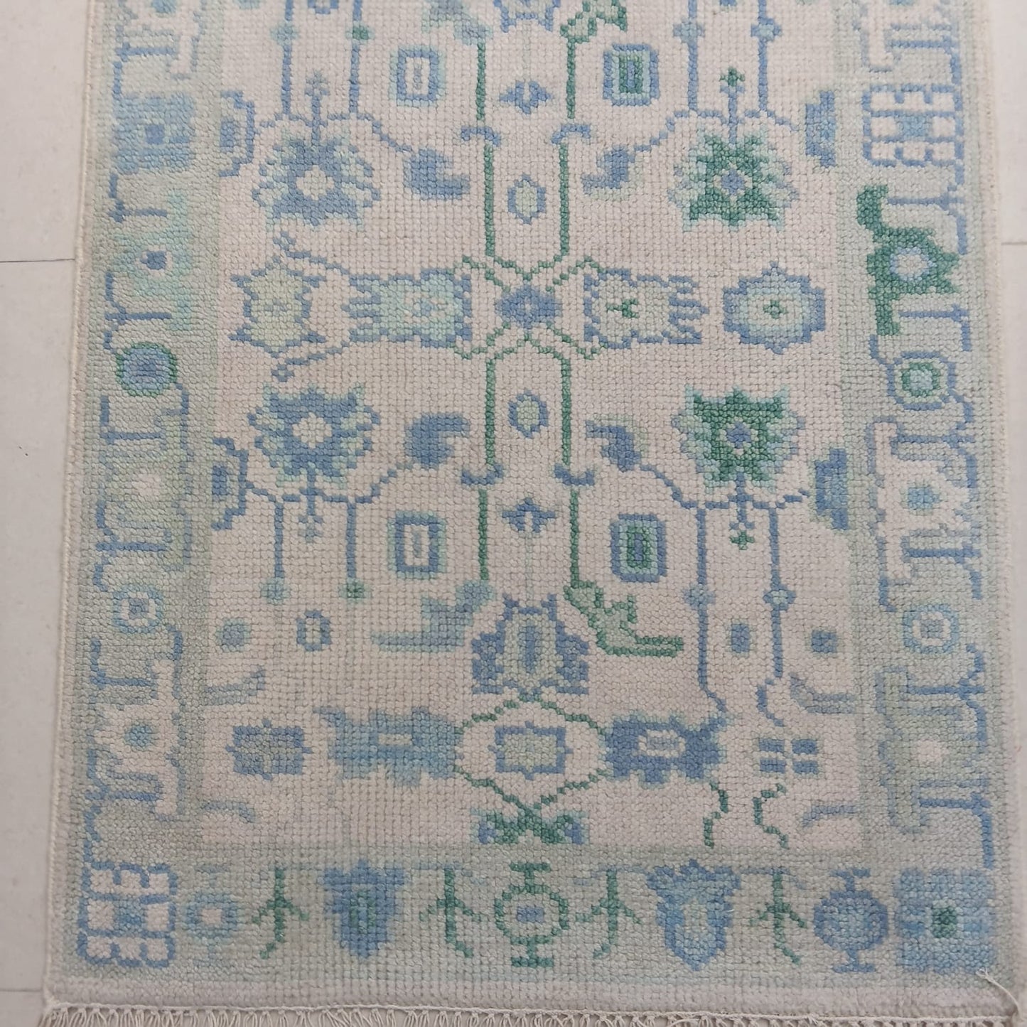 Patterned rug with blue and green designs on a light background