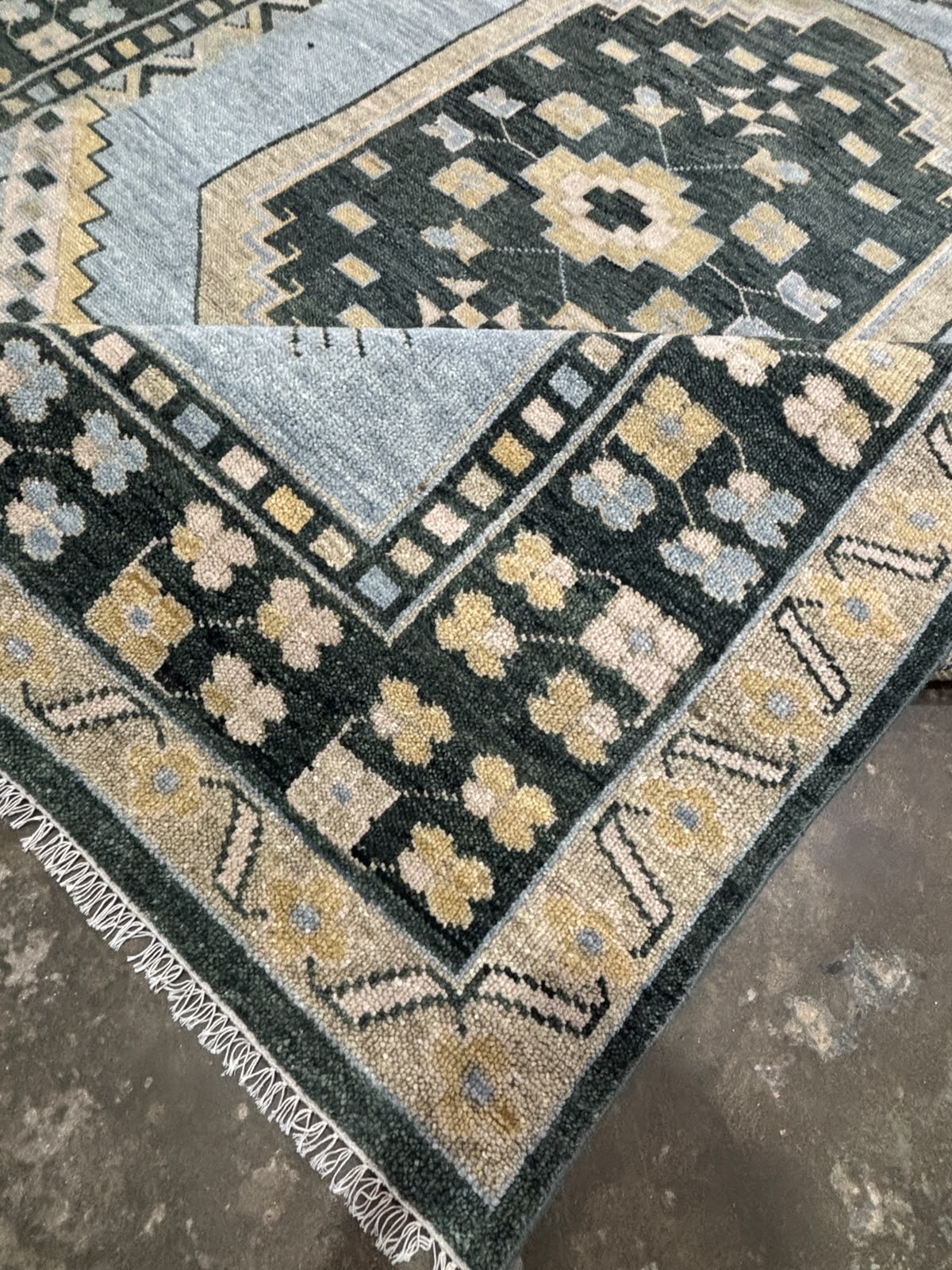 Folded handmade vintage blue Oushak wool rug displaying dense pile, soft texture, and handcrafted finish.