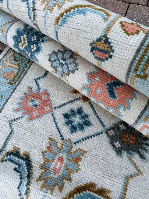 Close-up texture of a handmade vintage wool runner rug with ivory background and traditional Oushak motifs.