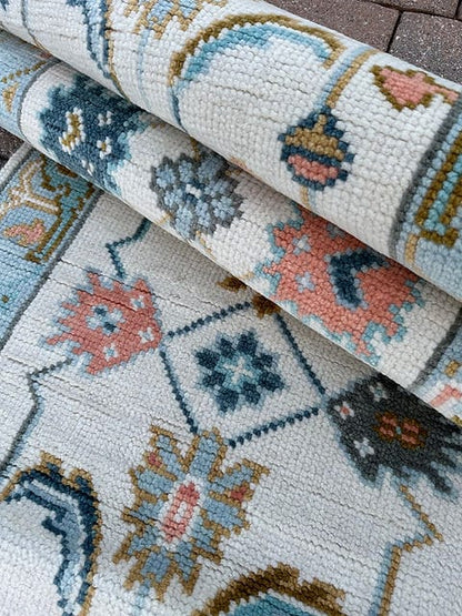 Close-up texture of a handmade vintage wool runner rug with ivory background and traditional Oushak motifs.
