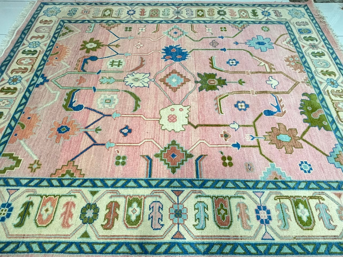 Traditional floral and geometric pattern on blush pink handmade Oushak rug.