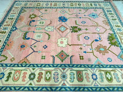 Traditional floral and geometric pattern on blush pink handmade Oushak rug.
